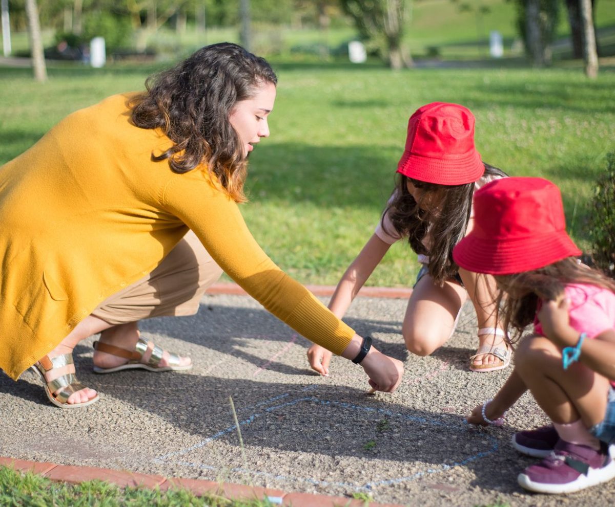 Mujer y niños agachados en un parque jugando juntos