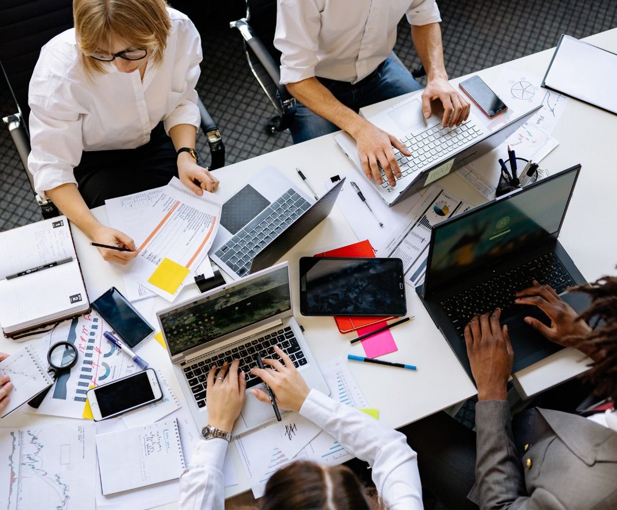 Equipo de personas trabajando juntas sobre una mesa con ordenadores y documentos
