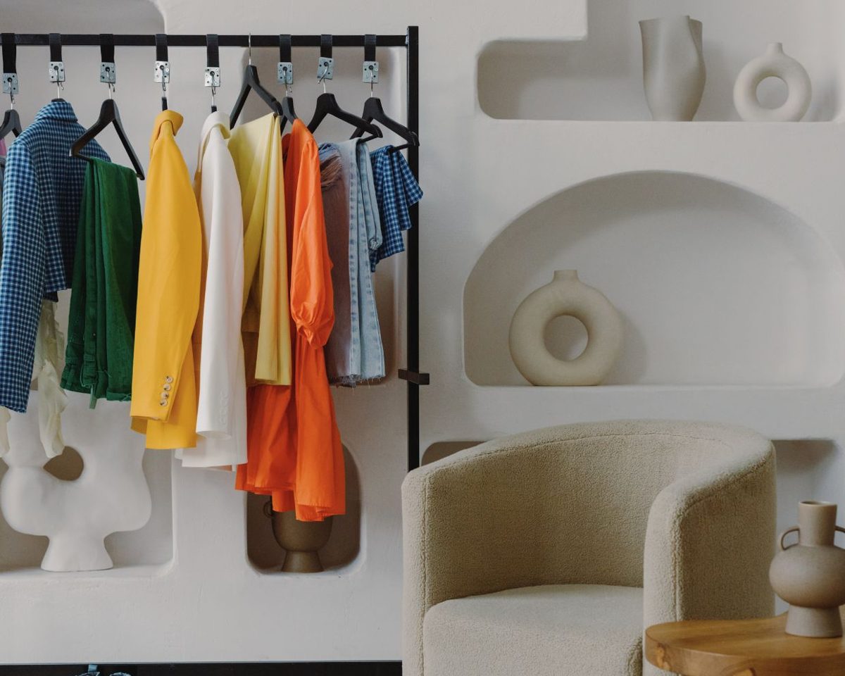 Percha con camisas y prendas de colores colgadas en un armario abierto