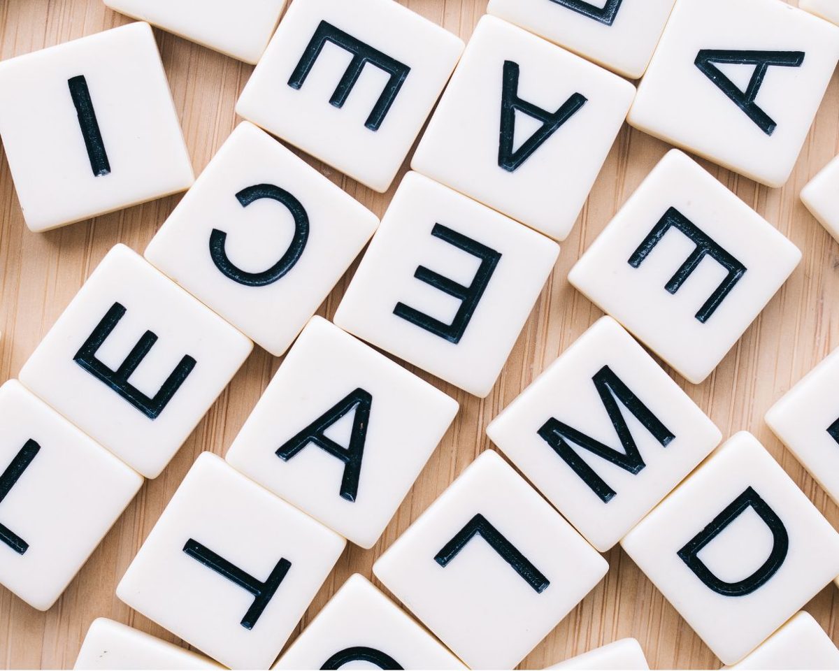 Fichas de scrabble con letras sueltas esparcidas sobre una mesa de madera
