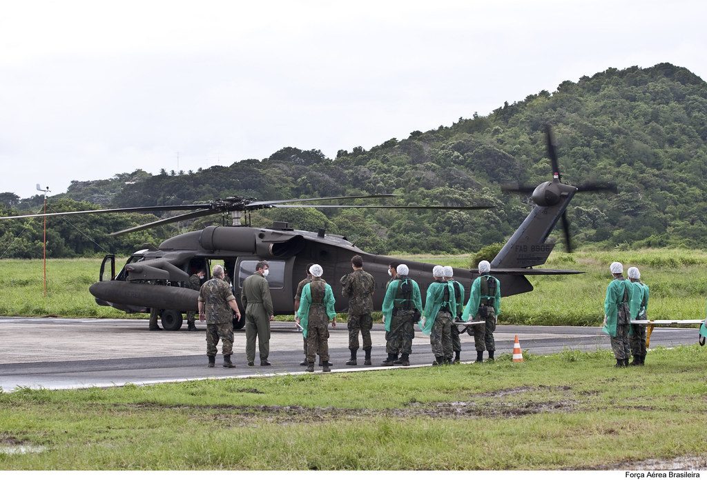 Helicóptero y personal con uniforme verde en una explanada de campo