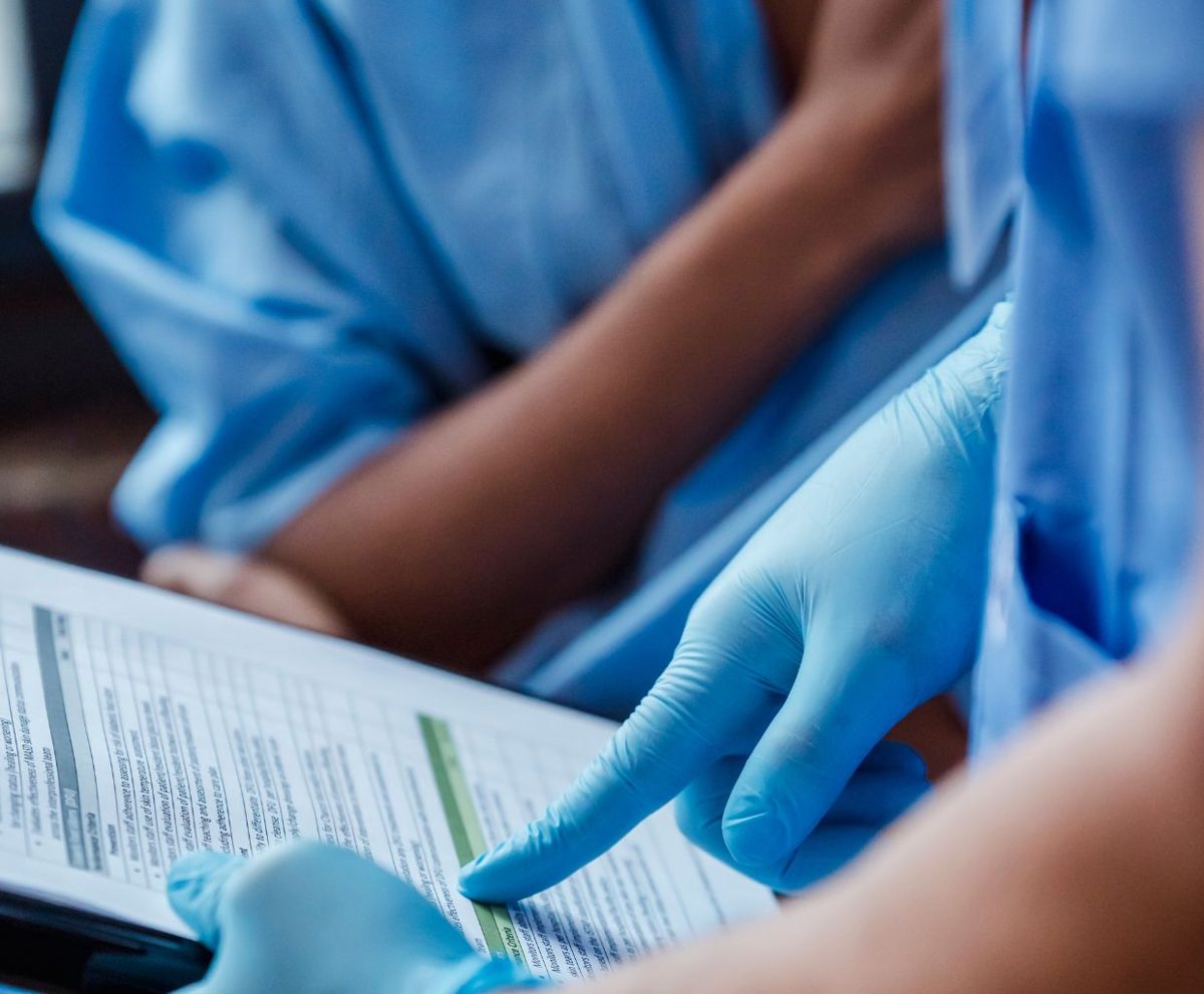 Manos con guantes sanitarios señalando un documento clínico