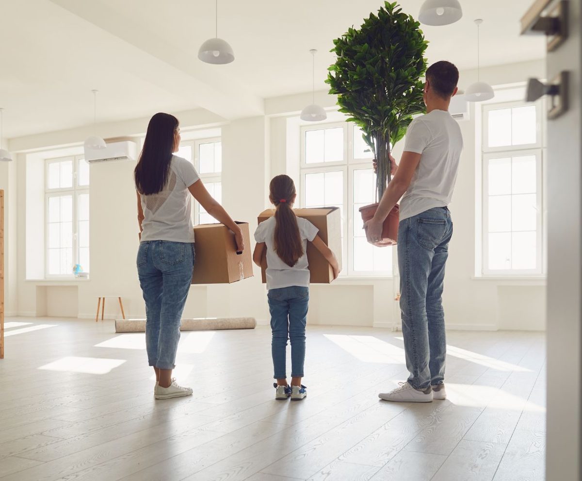 Un hombre, una mujer y una niña con cajas de mudanza en una vivienda vacía