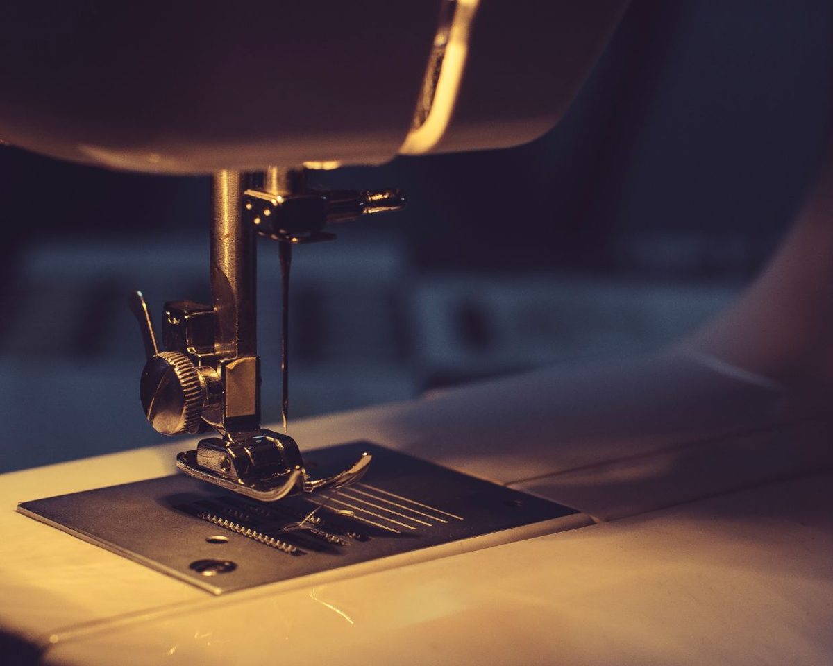 Máquina de coser iluminada con una luz cálida sobre una tela