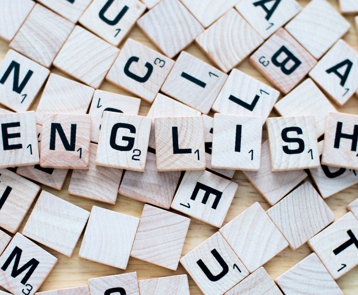 Fichas de madera de scrabble que forman la palabra ENGLISH sobre una mesa con otras letras sueltas
