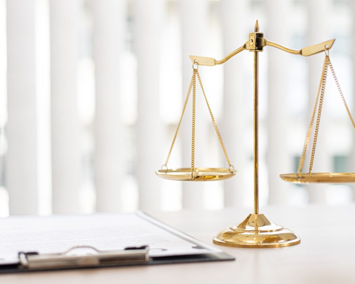 Balanza dorada de la justicia sobre una mesa junto a un portapapeles