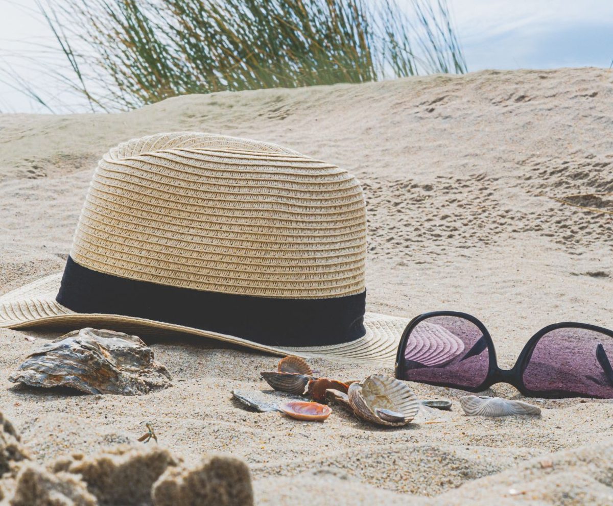 Sombrero de paja y gafas de sol sobre la arena de una playa