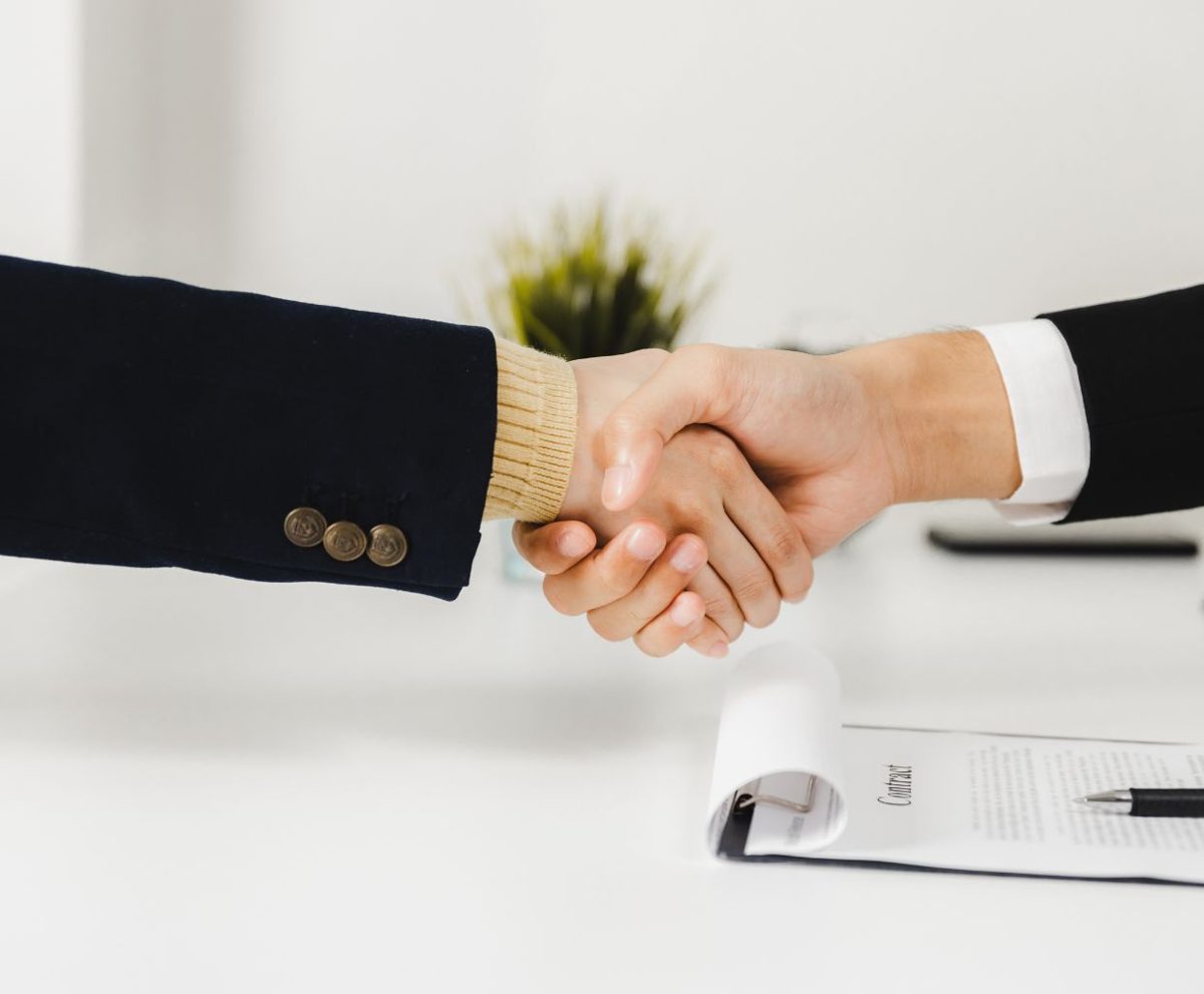 Dos personas dándose la mano sobre una mesa de reuniones