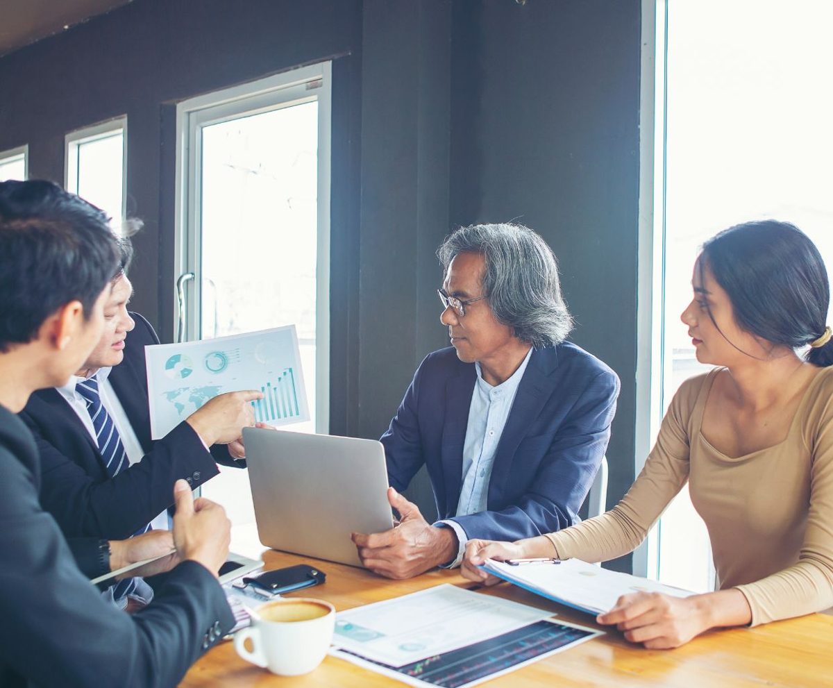 Reunión de trabajo con varias personas mirando documentos sobre la mesa