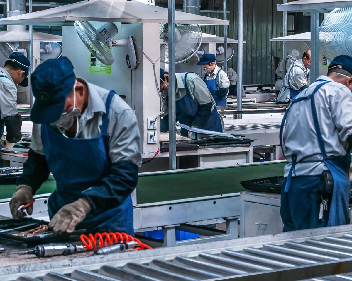 Operarios con uniforme trabajando en una línea de producción en una fábrica