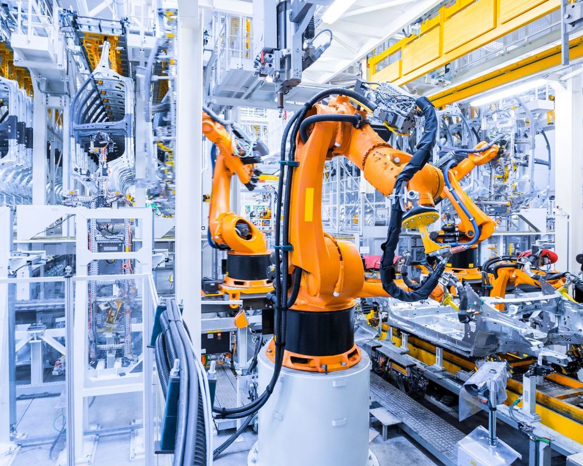 Brazos robóticos naranjas trabajando en una fábrica automatizada