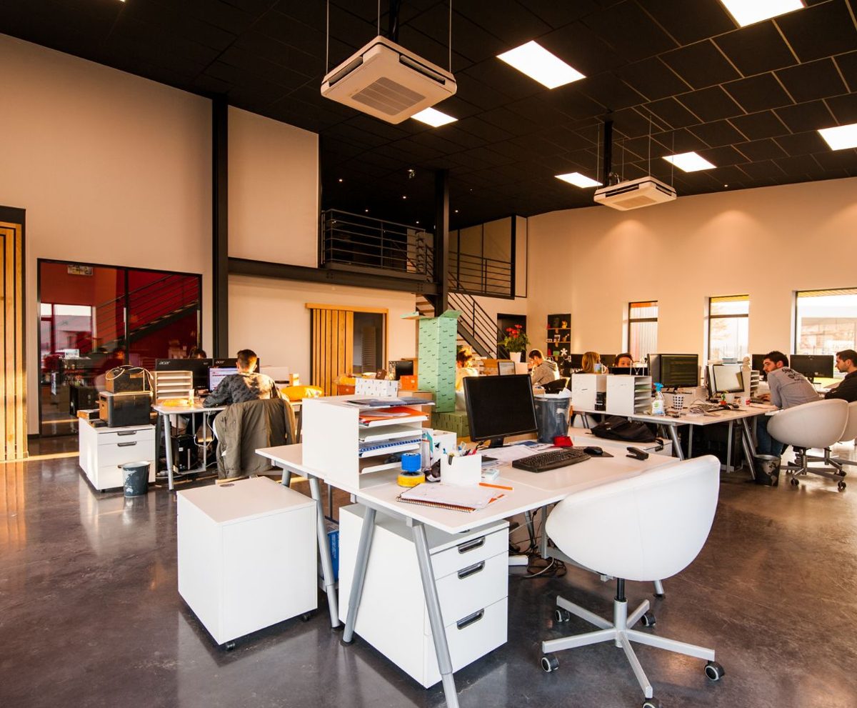 Oficina diáfana con mesas compartidas y personas trabajando en un espacio moderno